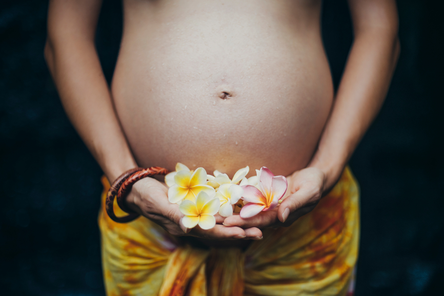 image of a pregnant woman holding flowers in front of her stomach
