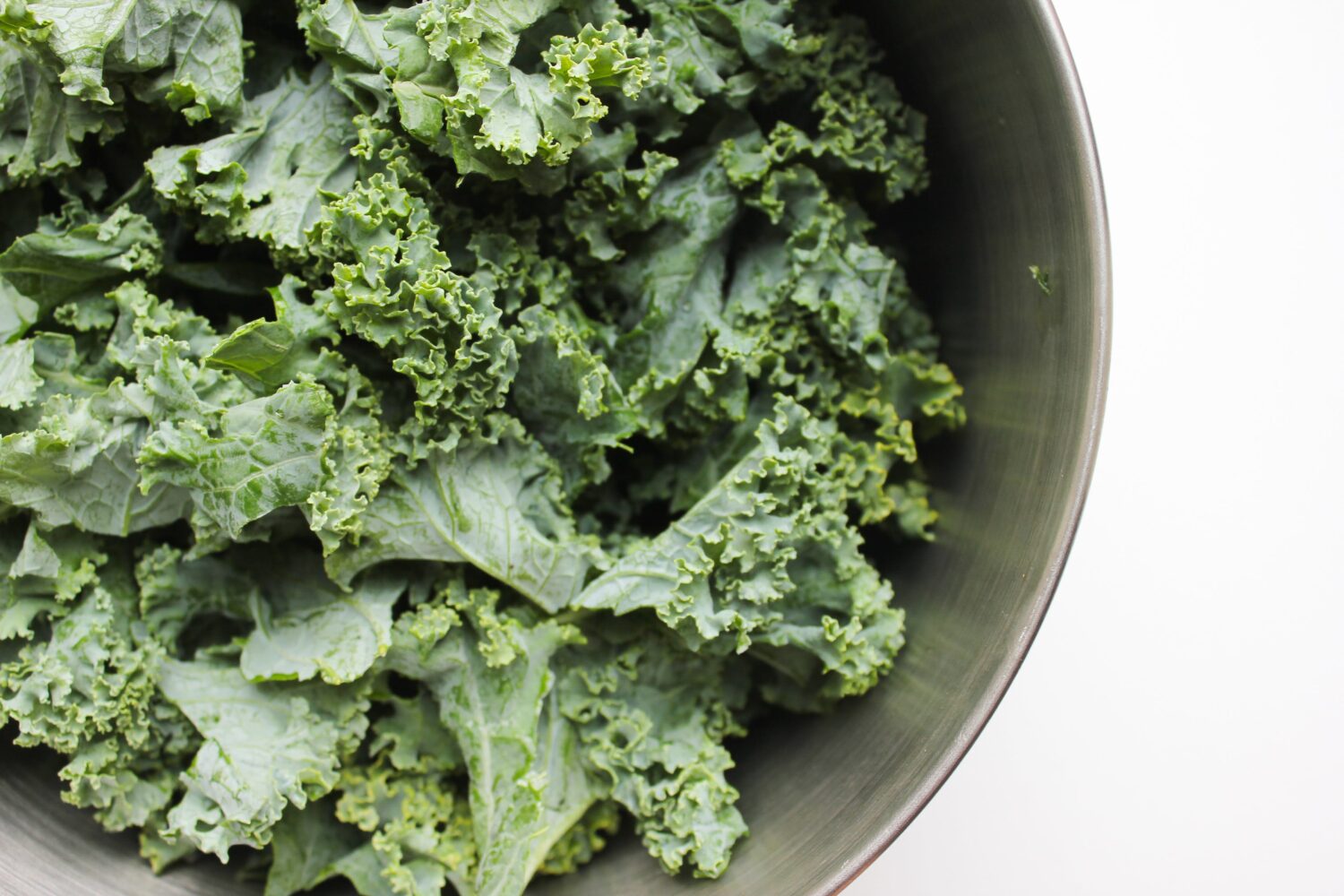 debloat, Zoomed-in image of raw green kale in a large metal bowl.