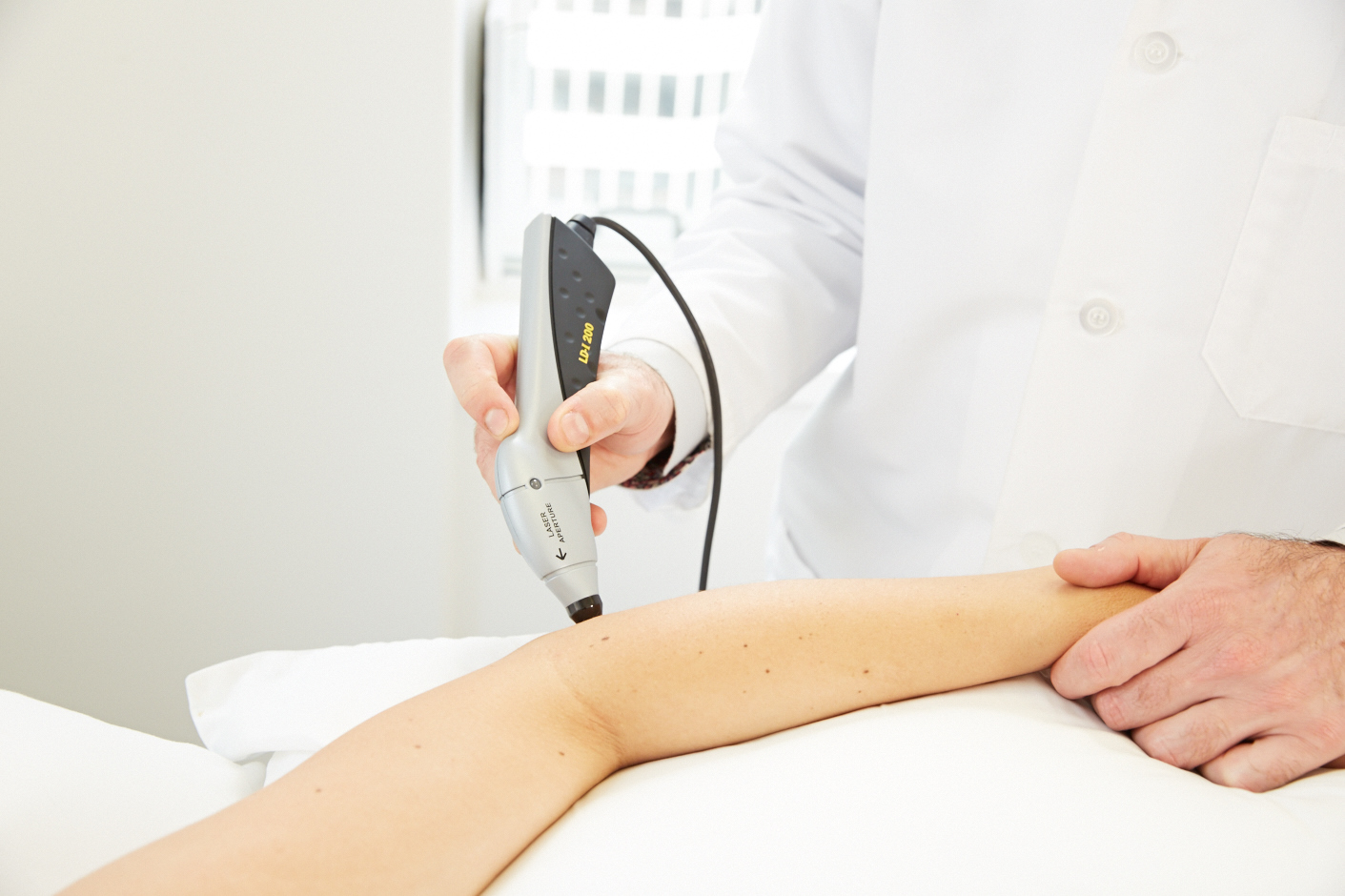 PBM Therapy & Laser Therapy, image of a physician using a PBM Therapy and Laser Therapy device on a patient's elbow.